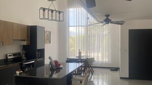 A modern kitchen with a central island, bar stools, and a ceiling fan. - Equipped house in Liberia for long stays (Liberia)
