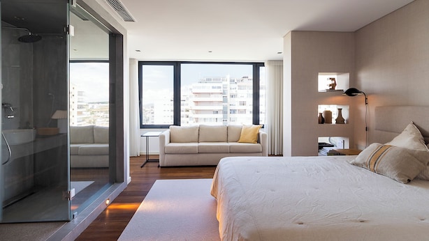 Une chambre moderne avec un grand lit, une douche en verre, un canapé et une vue sur la ville.