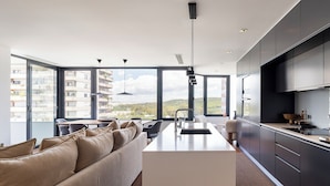 Une cuisine moderne dotée d’un îlot central, de grandes fenêtres et offrant une vue sur le paysage urbain.