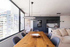 A modern interior with a dining table, chairs, a sofa, and a kitchen area. - Luxury 2BR Penthouse with balcony near historic Belem with AC in charming Lisboa (Lisboa)