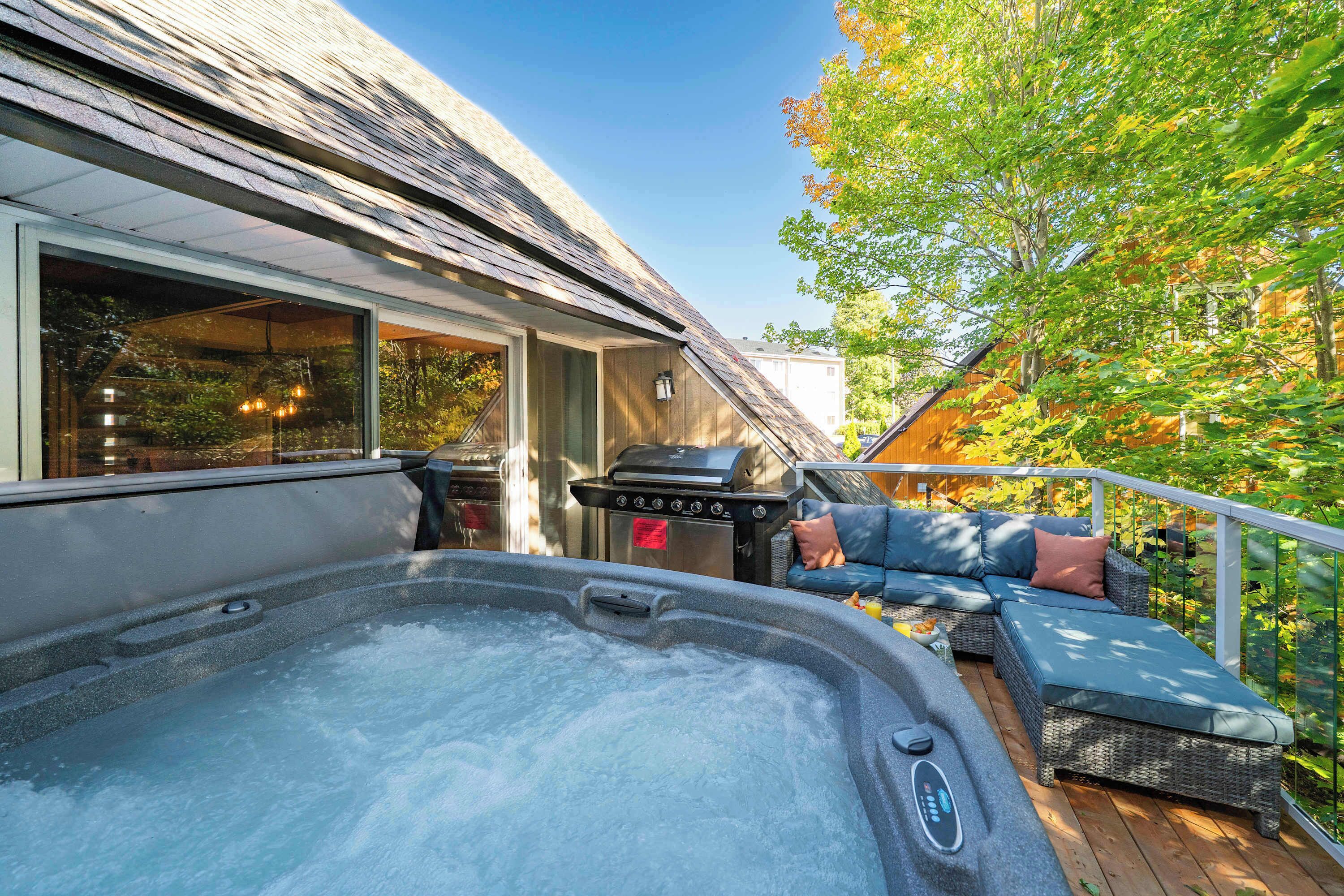 Ein Whirlpool auf einer Terrasse mit Grill und Sitzgelegenheiten.