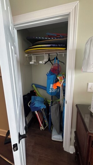 A storage closet with shelves, a rack, and a hanging bag.