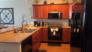 A kitchen with wooden cabinets, a stainless steel microwave, a dishwasher, and a refrigerator.