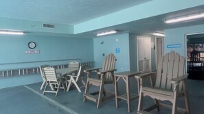 A poolside area with a table and chairs, a clock, and a sign indicating no smoking on the pool deck.
