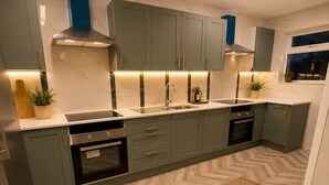 A modern kitchen with grey cabinets, a central island, and a herringbone-patterned floor.