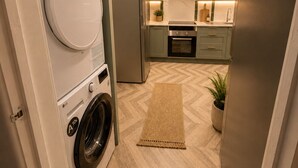 A compact kitchen with a washing machine, a microwave, and a built-in oven.
