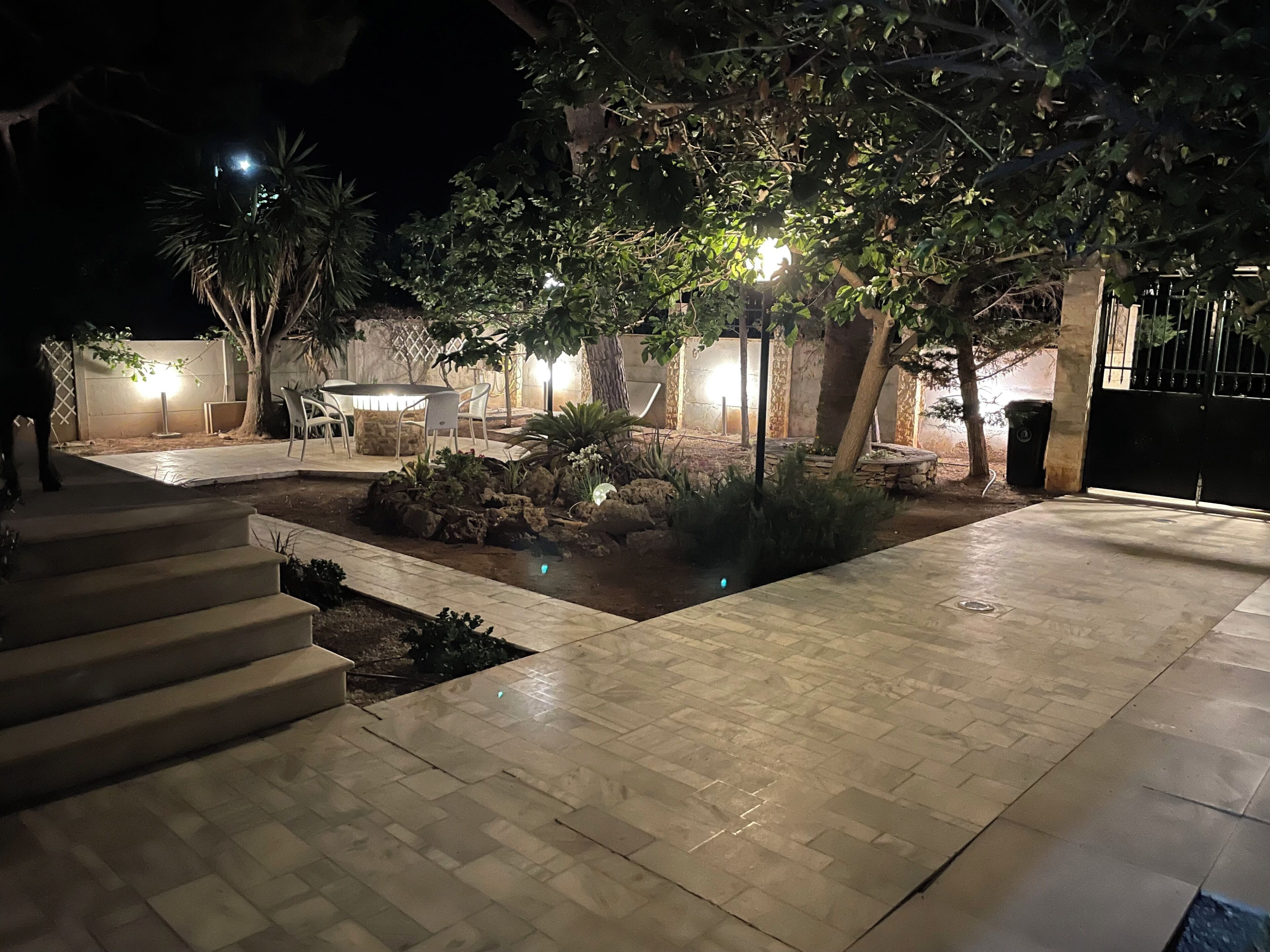 A well-lit outdoor patio area with a stone floor, a small water feature, and a seating area with chairs.