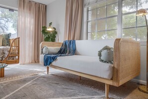 A modern living room with a white sofa, a large plant, and a floor lamp. - Bright spacious beautifully designed pool home with fireplace fast wifi sleeps 8 (Fort Pierce)