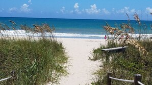 A beach path leading to the ocean, surrounded by grass and a wooden structure. - Casa Sol Boho chic pool home, sun soaked & spacious, king bed fireplace sleeps 8 (Fort Pierce)