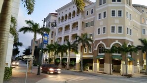 A multi-story hotel with balconies, palm trees, and a 'One Way' street sign. - Casa Sol Boho chic pool home, sun soaked & spacious, king bed fireplace sleeps 8 (Fort Pierce)