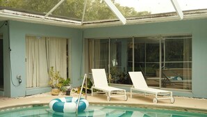 A swimming pool with lounge chairs and a pool float. - Casa Sol Boho chic pool home, sun soaked & spacious, king bed fireplace sleeps 8 (Fort Pierce)
