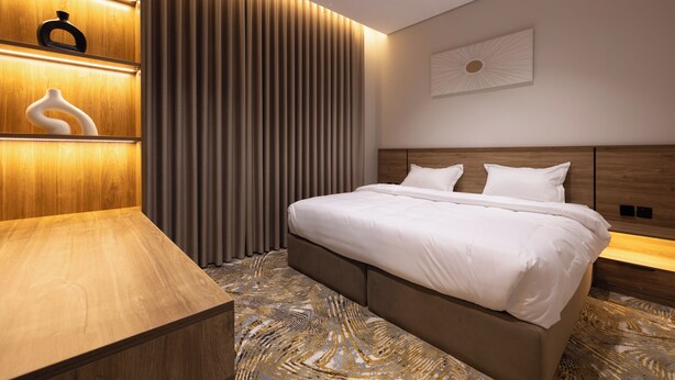 Un dormitorio moderno con una cama grande, cabecera de madera y mesita de noche integrada.