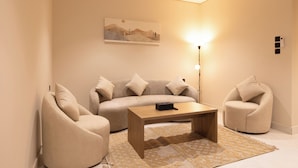Una sala de estar moderna con un sofá, dos sillones, una mesita de centro y una lámpara de pie.