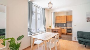 A modern kitchen with wooden cabinets, a dining table with chairs, and a green sofa. - Lively City Getaway for 10 Near Meir (Antwerp)