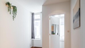 A bedroom with a bed, a window, a door leading to a bathroom, and a plant on the wall. - Lively City Getaway for 10 Near Meir (Antwerp)