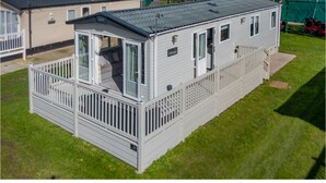 A mobile home with a fenced porch, a small deck, and a covered outdoor area. - A luxury Caravan in a suburb location. 
       AJH Holiday Homes, Ty Mawr. (Towyn)