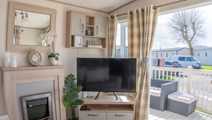 A cozy living room with a fireplace, television, and comfortable seating. - A luxury Caravan in a suburb location. 
       AJH Holiday Homes, Ty Mawr. (Towyn)