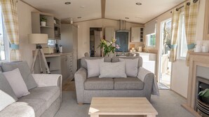 A cozy living room with a sofa, a coffee table, and a kitchen area in the background. - A luxury Caravan in a suburb location. 
       AJH Holiday Homes, Ty Mawr. (Towyn)