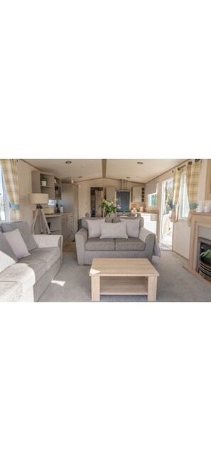 Ein gemütliches Wohnzimmer mit einer Couch, einem Couchtisch und einer Küche im Hintergrund.