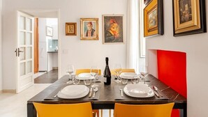 Comedor con mesa dispuesta para cuatro personas, obra de arte enmarcada en la pared y una pared de acento roja.