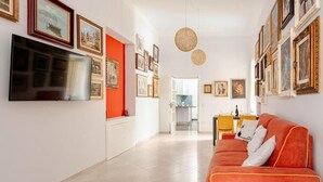 Una sala de estar moderna con televisor de pantalla plana, una pared de acento roja y un sofá con cojines.