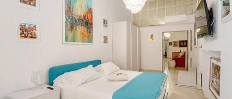 Een moderne slaapkamer met een bed, nachtkastje en kunstwerken aan de muur.