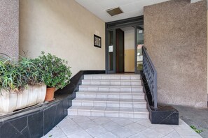Eine Treppe mit schwarzer Handlauf, die zu einer Tür mit Glasfenster führt.