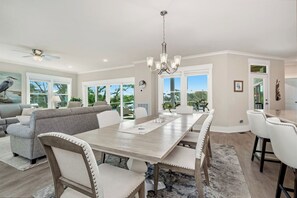 Une salle à manger spacieuse avec une longue table, des chaises blanches et un lustre.