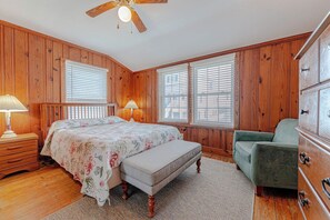 Ein Schlafzimmer mit Holzvertäfelung, einem Bett, einer Bank, einem Schminktisch und einem Sessel.