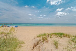 Ein Strand mit einer Holzsteganlage, Sonnenschirmen und Dünen.