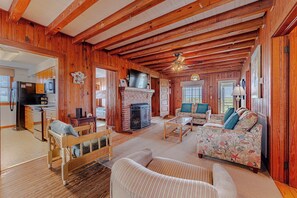 A wooden interior with a fireplace, a television, and a sofa with floral upholstery. - JL #426 | J. Jones - Oceanfront - Pet Friendly (Nags Head)