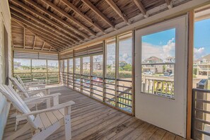 Un espace extérieur abrité, doté d’un plancher en bois, d’une rambarde et offrant une vue sur un quartier résidentiel.