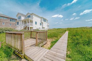A two-story beachfront house with a wooden deck and a pathway leading to it. - JL #426 | J. Jones - Oceanfront - Pet Friendly (Nags Head)