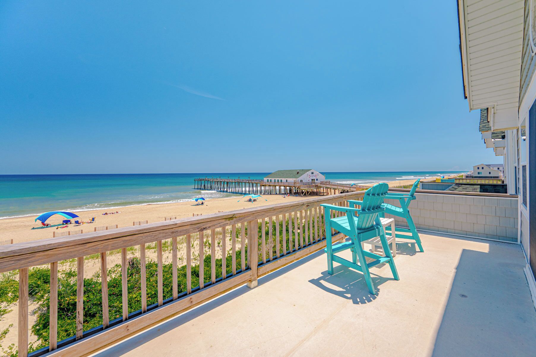 Un balcon avec vue sur la plage, une jetée et un bâtiment doté d’un toit végétalisé.