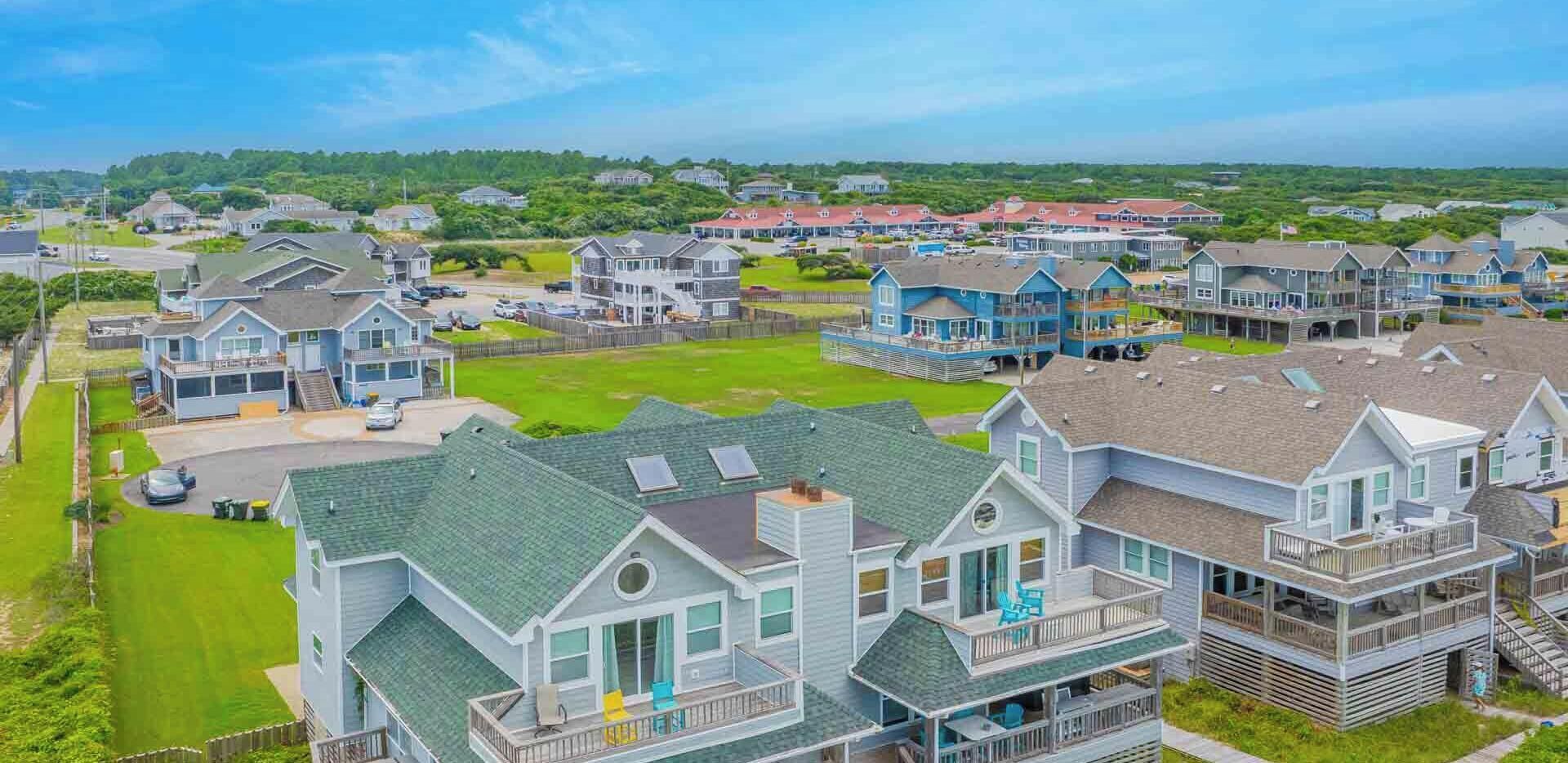 A coastal residential area with multiple two-story houses featuring balconies and a grassy front yard.