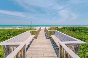 Ein Holzsteg, der zu Sitzgelegenheiten am Strand führt.