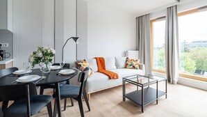 Una sala moderna con comedor, un sofá con almohadones coloridos, una mesa de centro de vidrio y vista al exterior.