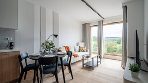 Una sala de estar moderna con comedor, un sofá con cojines, una cafetera y un televisor.