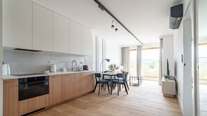 Una cocina moderna con armarios de madera, horno empotrado y comedor con mesa y sillas.