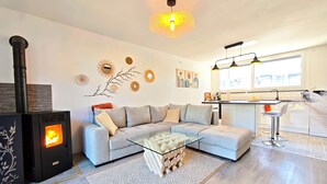 A modern living room with a sectional sofa, a glass coffee table, a fireplace, and a kitchen area with a bar. - La villa des cimes - Close to the lake (Tresserve)