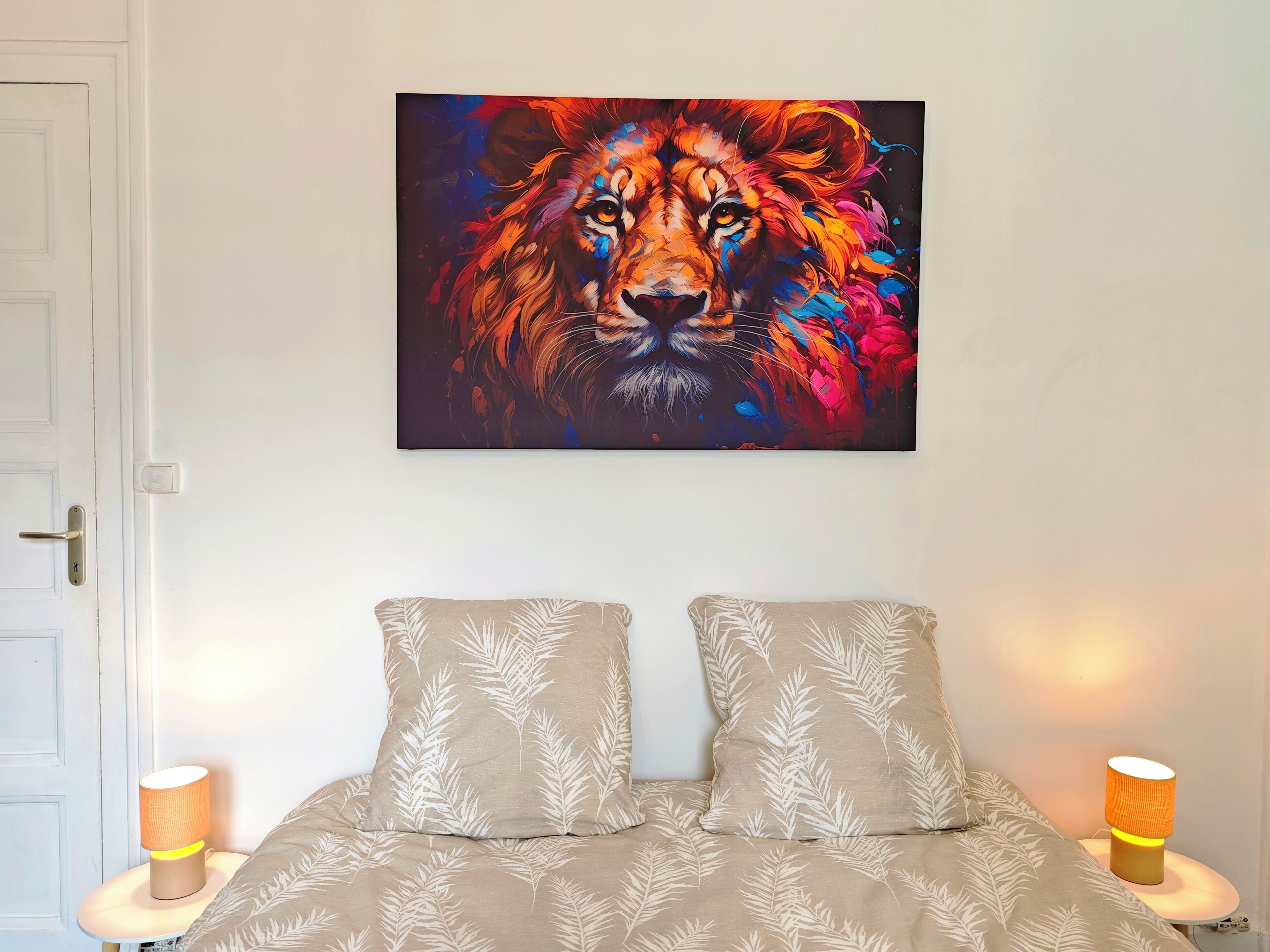 A bedroom with a bed, two pillows, a wall-mounted painting, and bedside lamps.