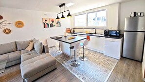 A modern kitchen with a dining area, a sofa, and a refrigerator. - La villa des cimes - Close to the lake (Tresserve)