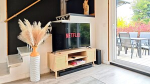 A modern living room with a TV, wooden entertainment unit, and a view of outdoor patio. - La villa des cimes - Close to the lake (Tresserve)