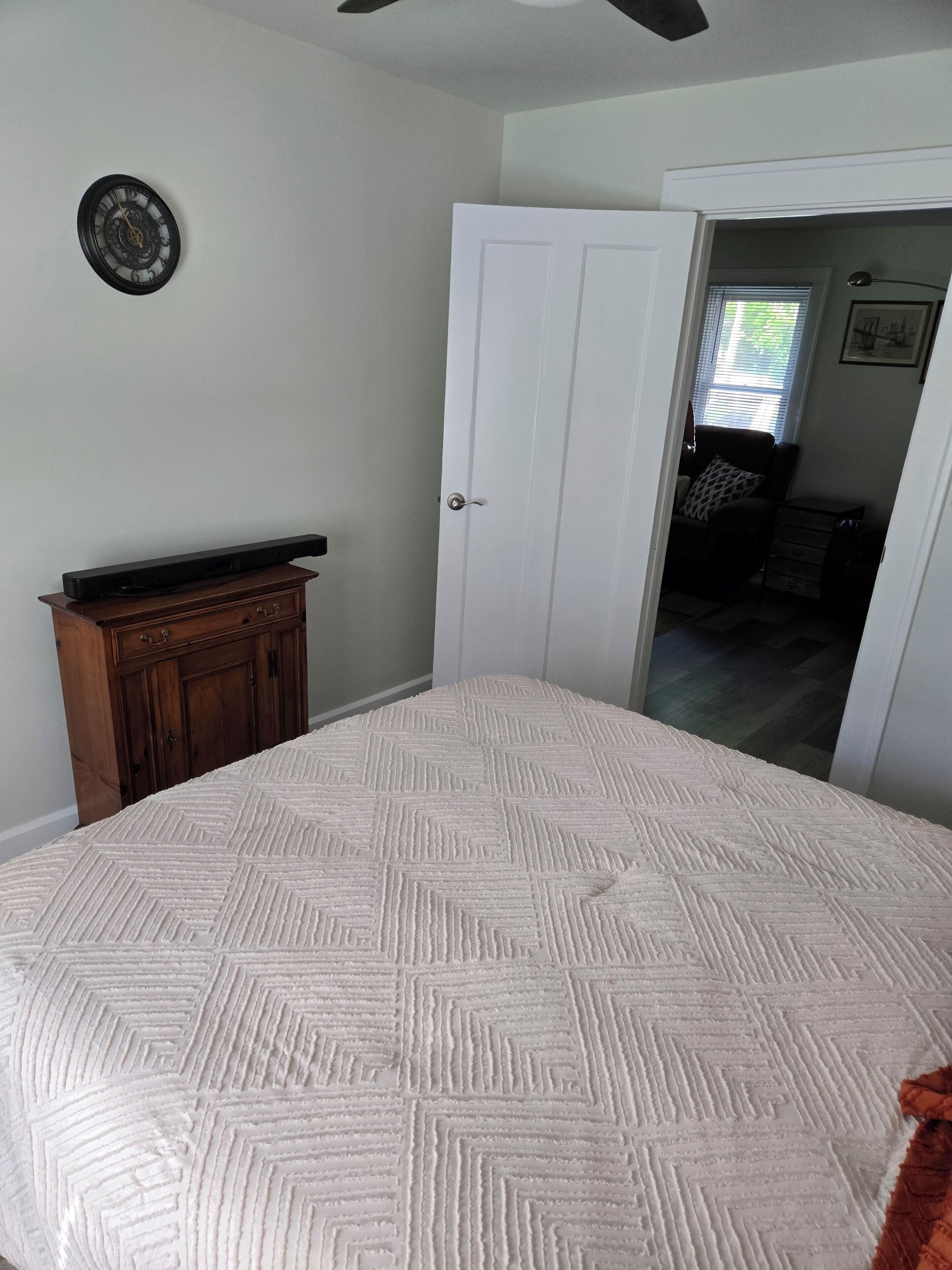 Une chambre à coucher avec un lit, une commode, une porte et un ventilateur de plafond.