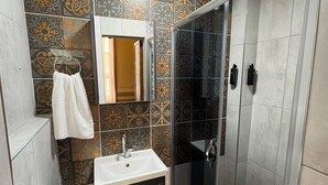 A bathroom with a shower, toilet, sink, and a towel rack.