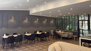 A modern cafe interior with a dining area, seating, and a large window offering a view.