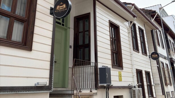 A two-story building with a green door, a signboard, and air conditioning units.
