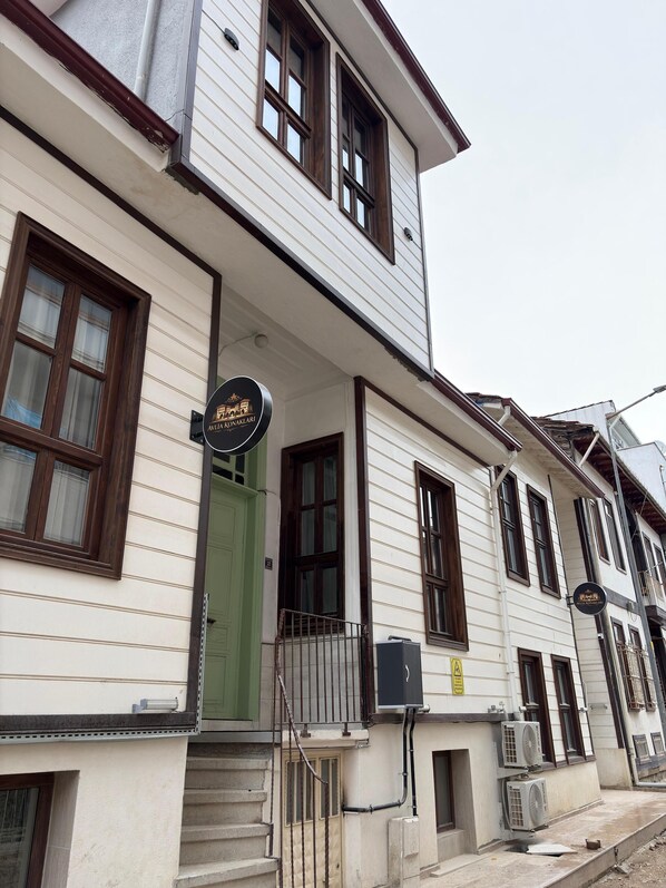 A two-story building with a green door, a signboard, and air conditioning units.
