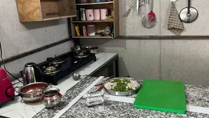Una cucina con un fornello a gas, un tostapane rosso e un tagliere verde sul piano di lavoro.