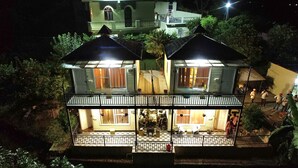 Un edificio a due piani con un balcone e una zona pranzo visibile all'interno.